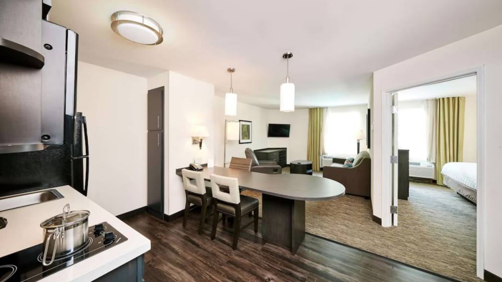 Sonesta Simply Suites Houston CityCentre I-10 West guest room, featuring a kitchen and lounge area, between which is a table and three chairs.