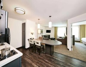 Sonesta Simply Suites Houston CityCentre I-10 West guest room, featuring a kitchen and lounge area, between which is a table and three chairs.