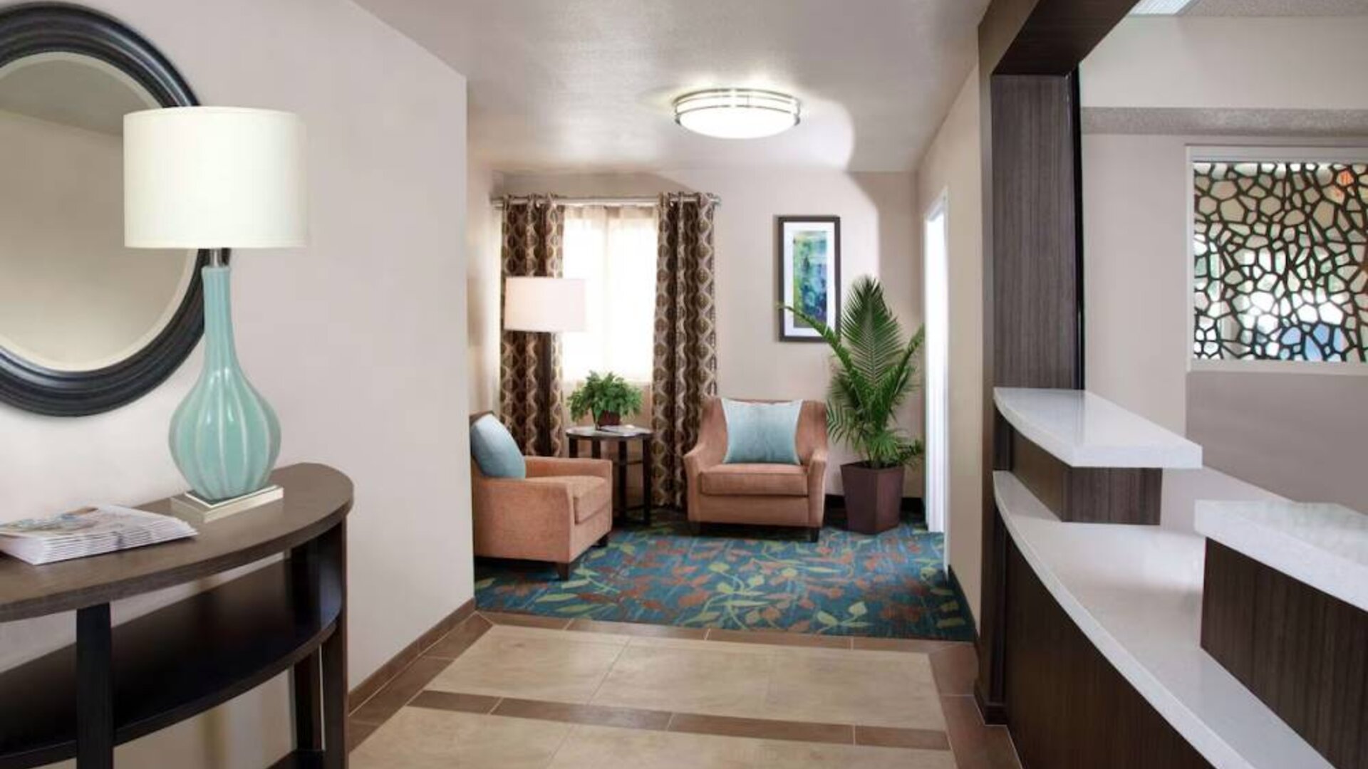 Sonesta Simply Suites Plano Frisco’s lobby features a pair of armchairs, window, coffee table, and potted plants.