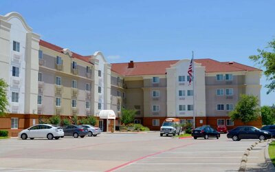 The hotel’s exterior has ample parking for guests, a US flag fluttering on a flagpole, and abundant greenery.