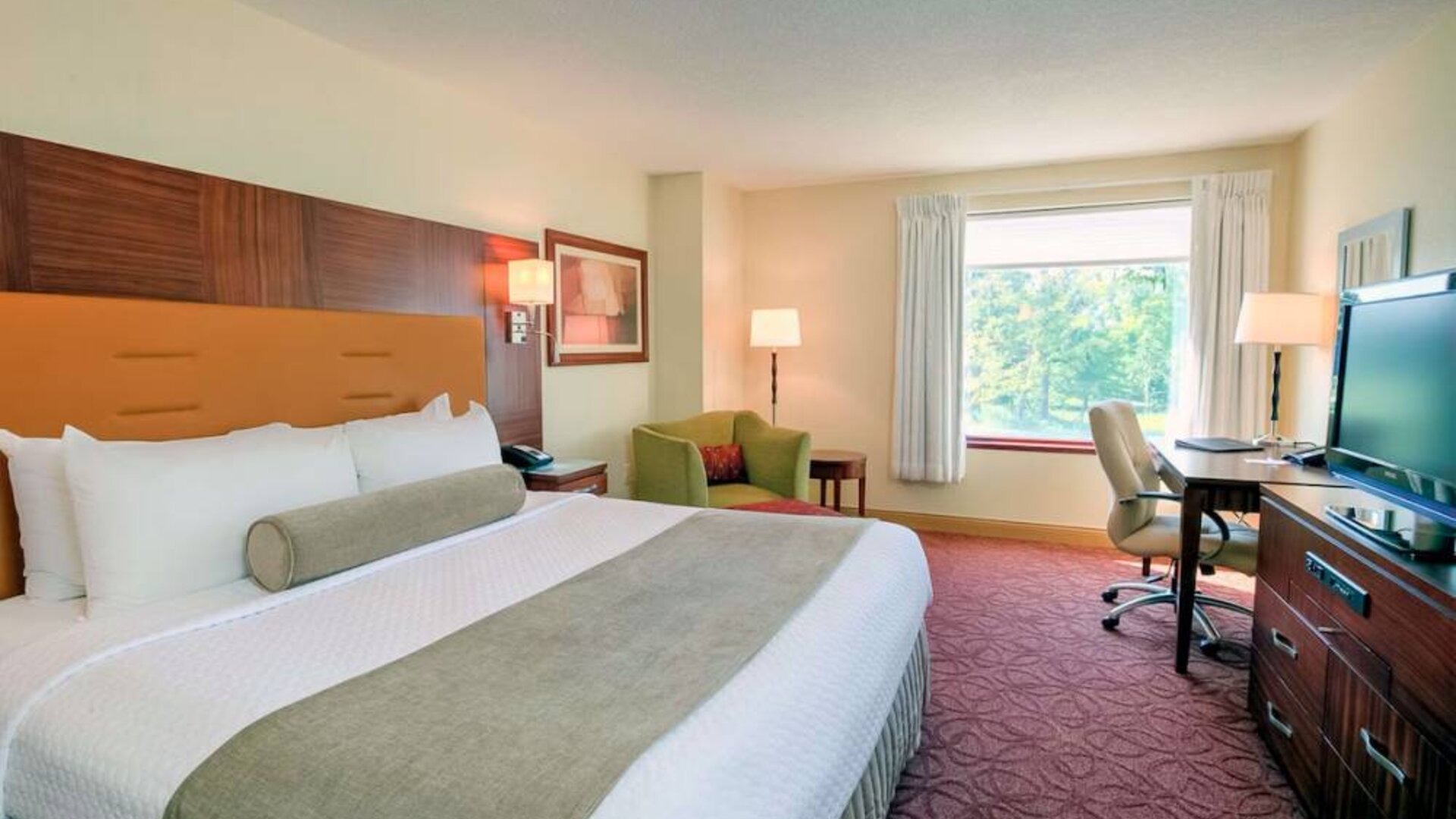 Double bed guest room in Sonesta Milwaukee West Wauwatosa, featuring armchair, window, and television.