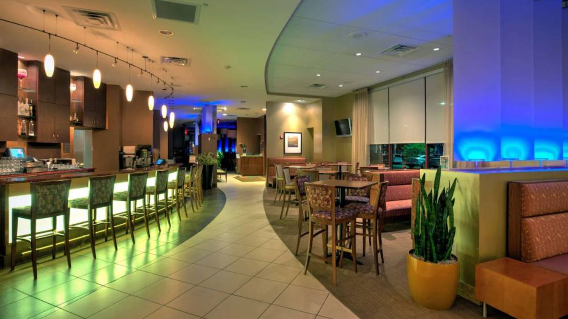 The hotel’s dining area has a mix of bar stool seating and tables and chairs, with subdued lighting providing a relaxed atmosphere.