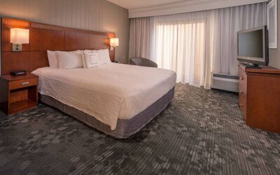 Double bed guest room in Sonesta Select Columbia, including a large window, chair, and TV.