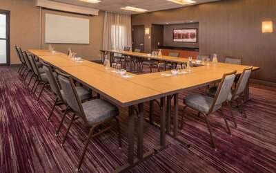 Meeting room in Sonesta Select Columbia, with tables arranged in a U-shape, seating for over a dozen attendees, and a whiteboard.