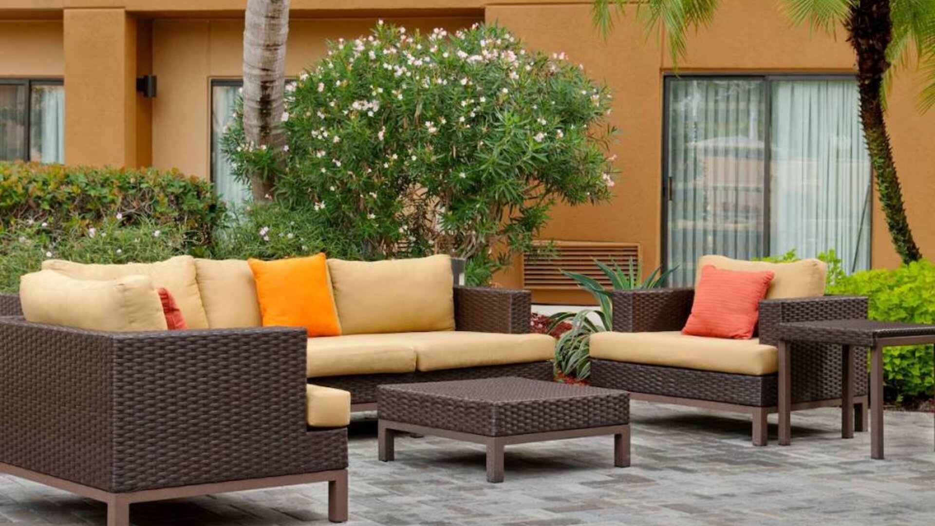 The hotel’s patio is furnished with armchair and sofa seating, plus coffee tables, and is surrounded by greenery.