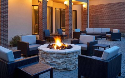 Sonesta Select Indianapolis Carmel’s patio features a fire pit and armchairs, plus coffee tables and sofa seating.
