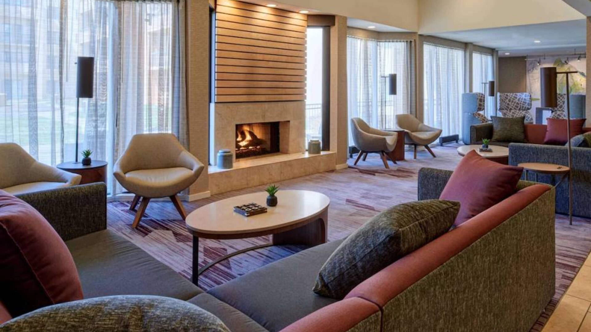 The lobby lounge in Sonesta Select Indianapolis Carmel has a mix of comfy chairs and large sofas, plus coffee tables and a fireplace.
