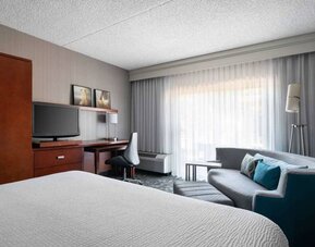 Sonesta Select Phoenix Camelback double bed guest room, furnished with TV, desk, chair, and a sofa.