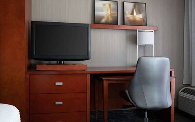 Sonesta Select Phoenix Camelback guest room workspace, including desk, chair, and lamp, plus a TV.