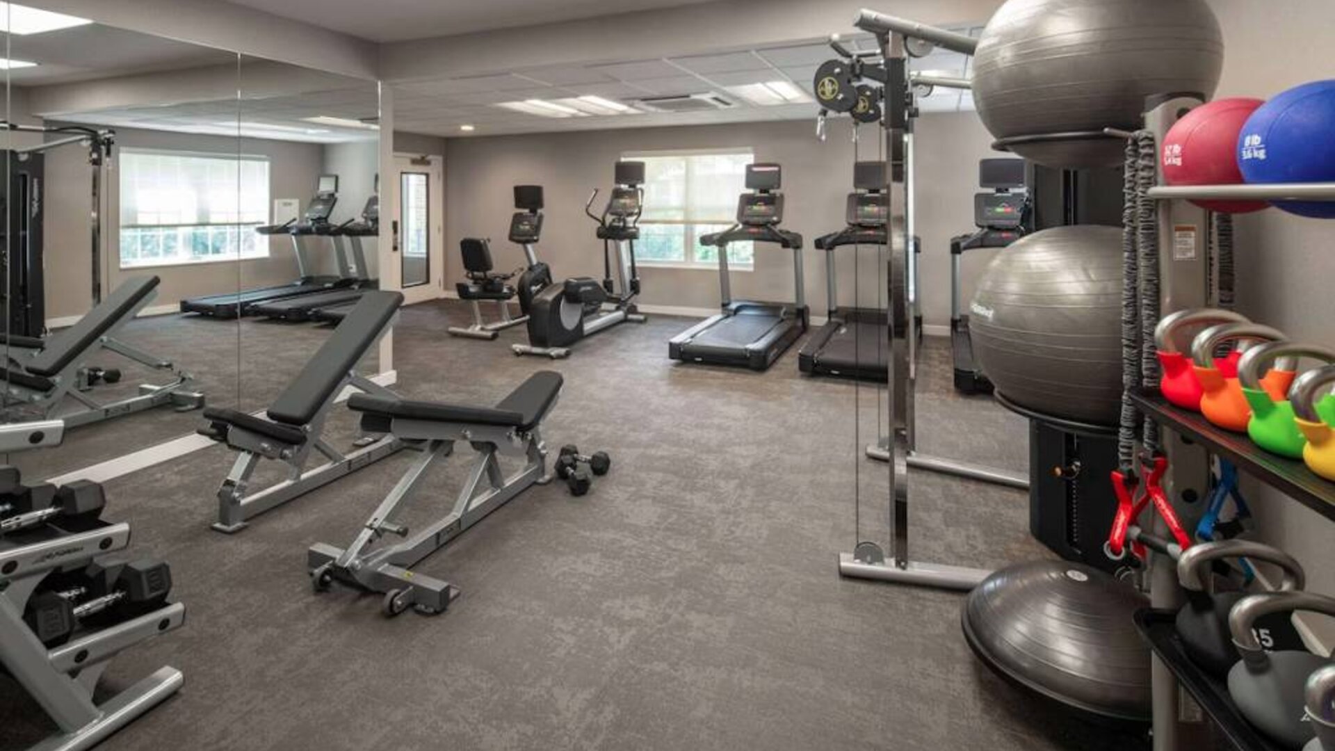 The fitness center at Sonesta ES Suites Fairfax Fair Lakes is equipped with dumbbells, kettlebells, gym balls, and assorted exercise machines.