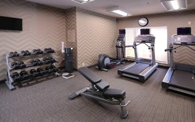 Sonesta ES Suites Dallas Medical Market Center’s fitness center has an assortment of exercise equipment including free weights, and a wall-mounted television.