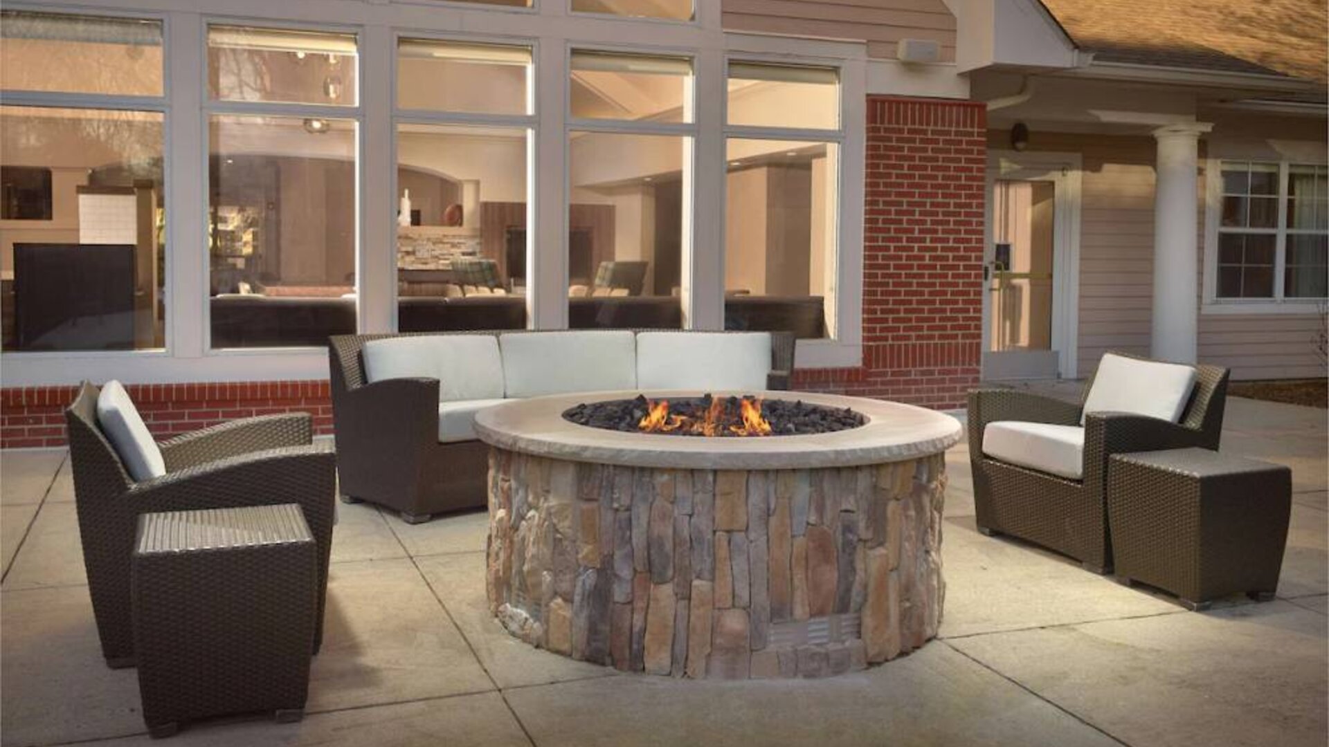 Fire pit surrounded by armchair and sofa seating, plus coffee tables, at Sonesta ES Suites Raleigh Durham Airport Morrisville.
