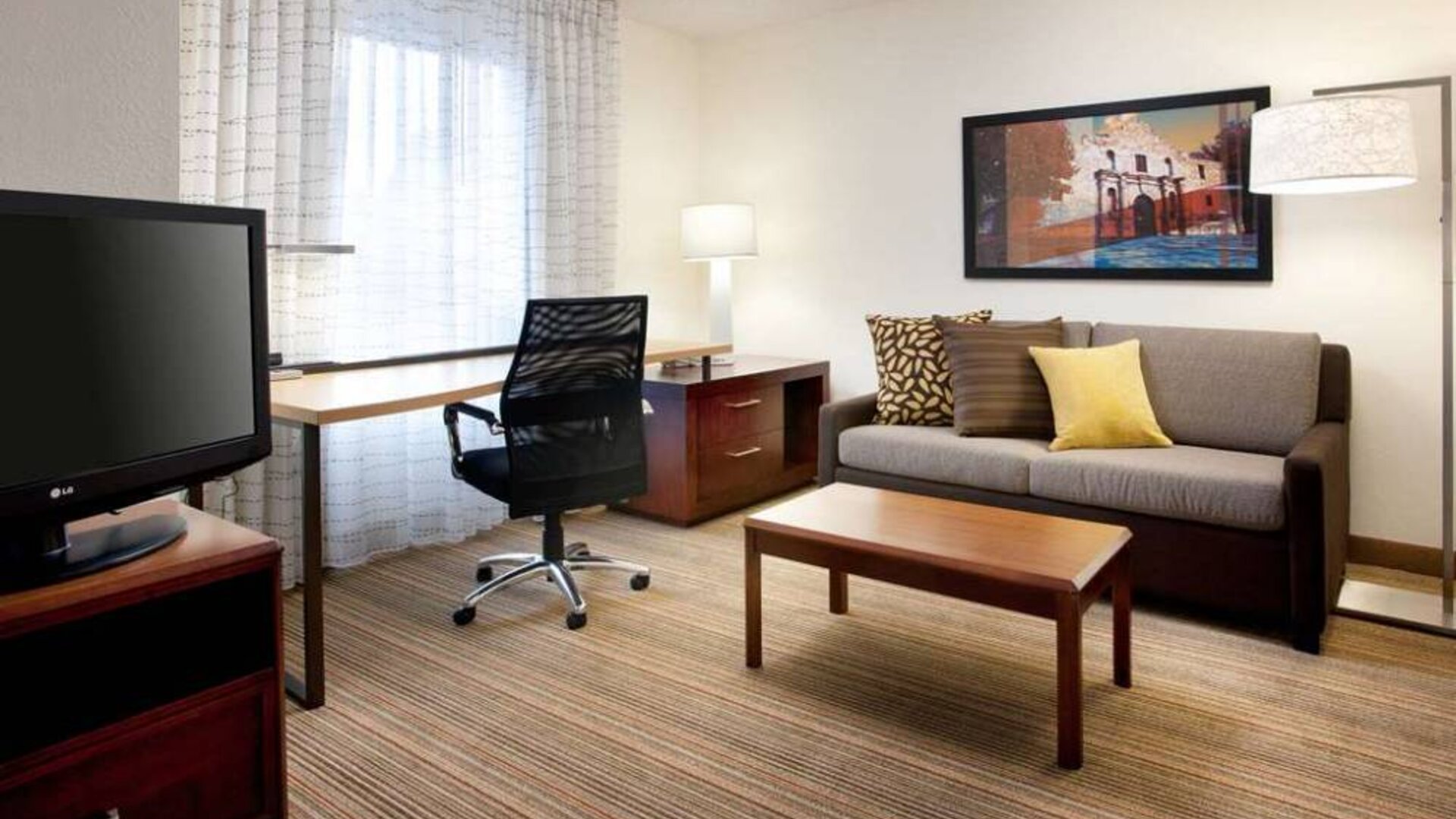 Guest room workspace desk and chair, with TV and sofa nearby, at Sonesta ES Suites San Antonio Downtown Alamo Plaza.