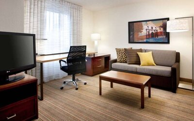 Guest room workspace desk and chair, with TV and sofa nearby, at Sonesta ES Suites San Antonio Downtown Alamo Plaza.