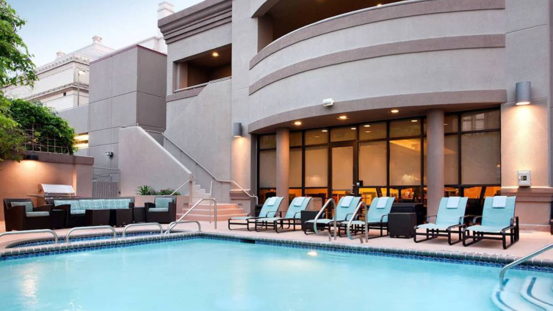 Sonesta ES Suites San Antonio Downtown Alamo Plaza’s outdoor pool has armchair and sofa seating by the side, as well as sun loungers.