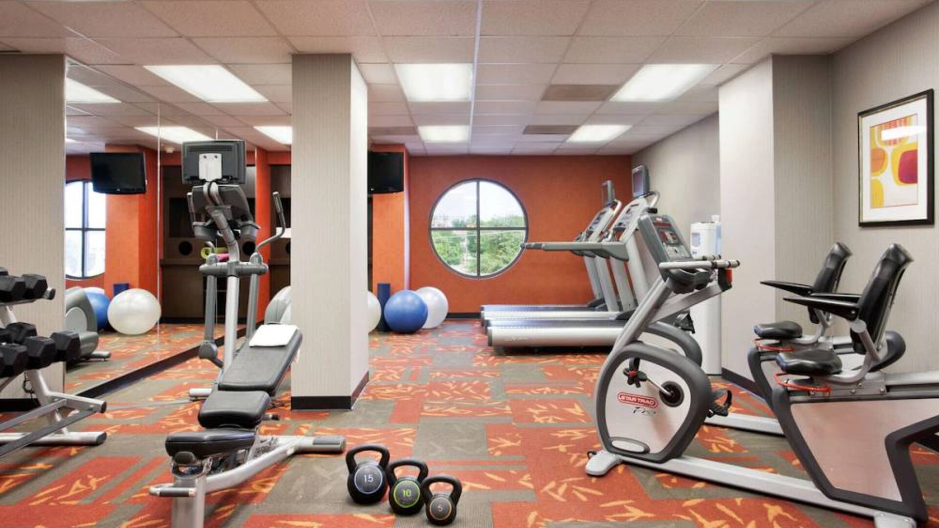 Fitness center with dumbbells, kettlebells, a variety of exercise machines and a TV, at Sonesta ES Suites San Antonio Downtown Alamo Plaza.