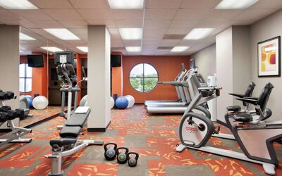 Fitness center with dumbbells, kettlebells, a variety of exercise machines and a TV, at Sonesta ES Suites San Antonio Downtown Alamo Plaza.