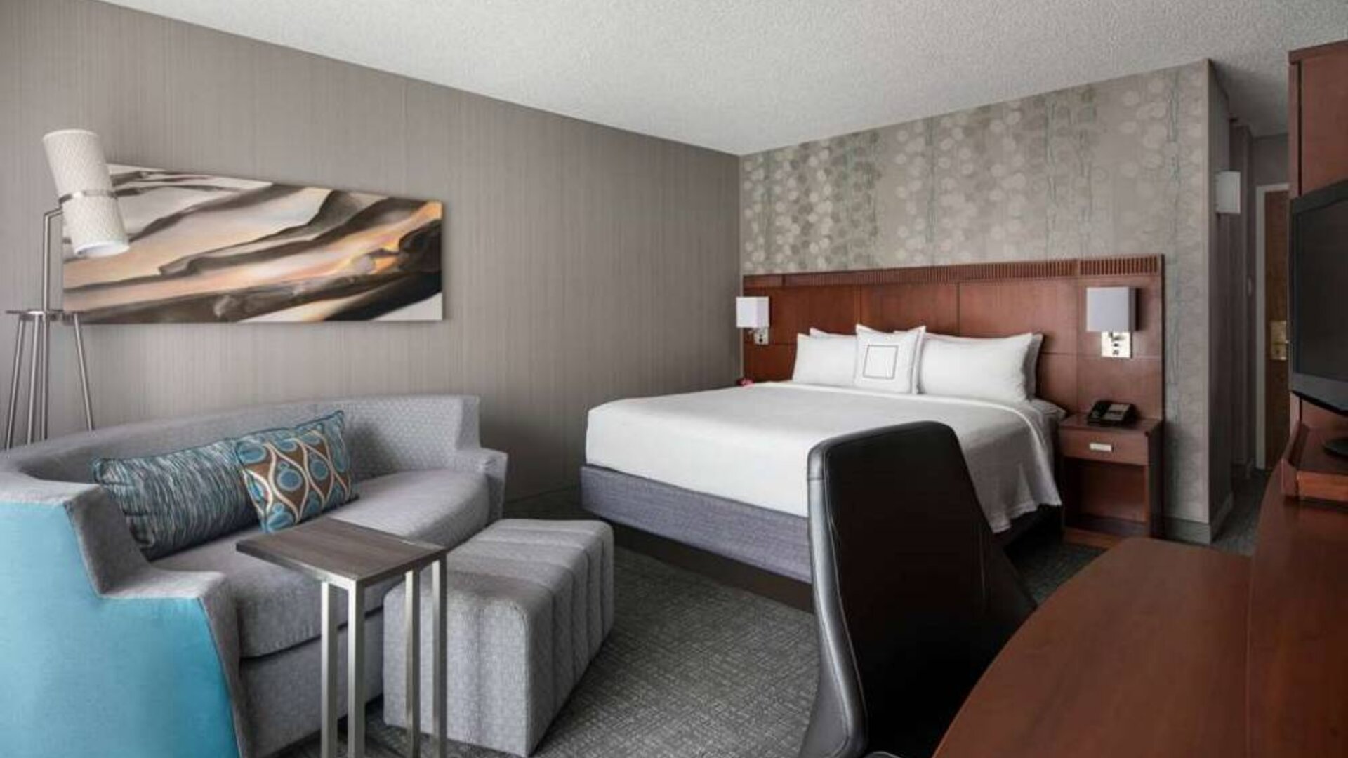 Sonesta Select Los Angeles LAX El Segundo double bed guest room including TV, chair, and sofa.