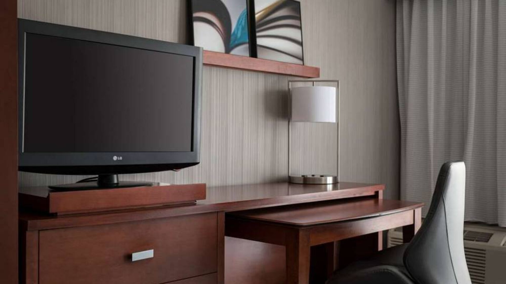 Guest room workspace in Sonesta Select Los Angeles LAX El Segundo, with chair, desk, lamp, and TV.