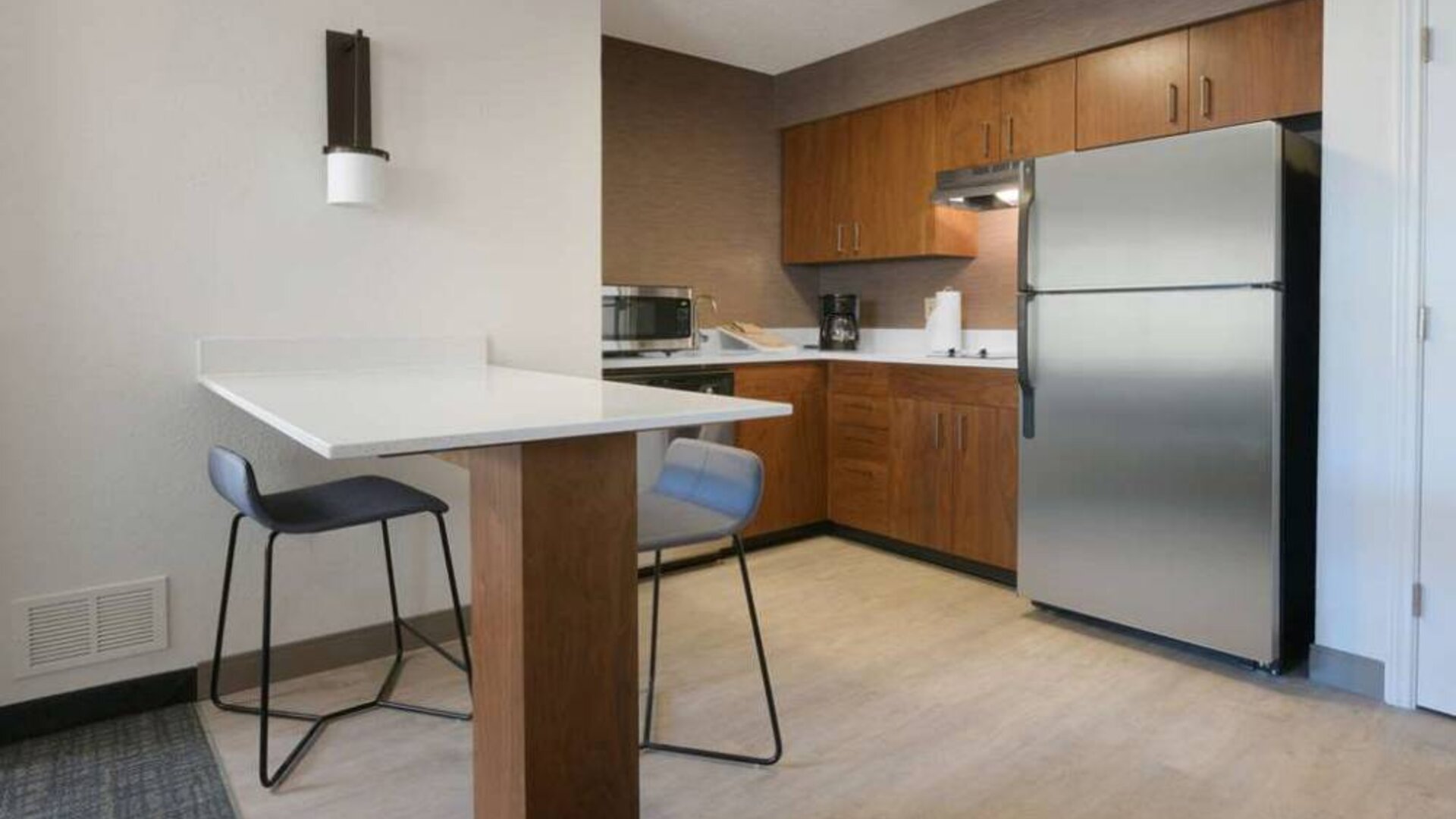 Sonesta ES Suites Fort Worth Fossil Creek guest room kitchen, featuring fridge-freezer, microwave, and table and chairs.