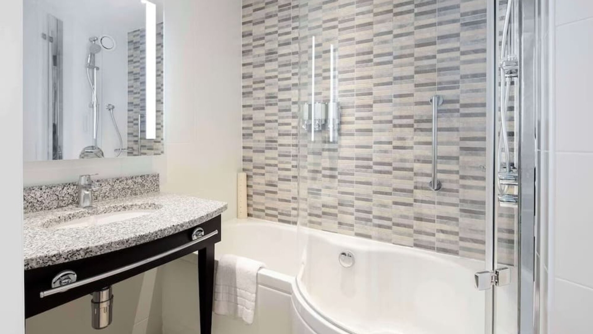 Guest bathroom with shower and bathat Hampton By Hilton London Stansted Airport.