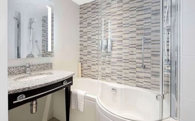 Guest bathroom with shower and bathat Hampton By Hilton London Stansted Airport.