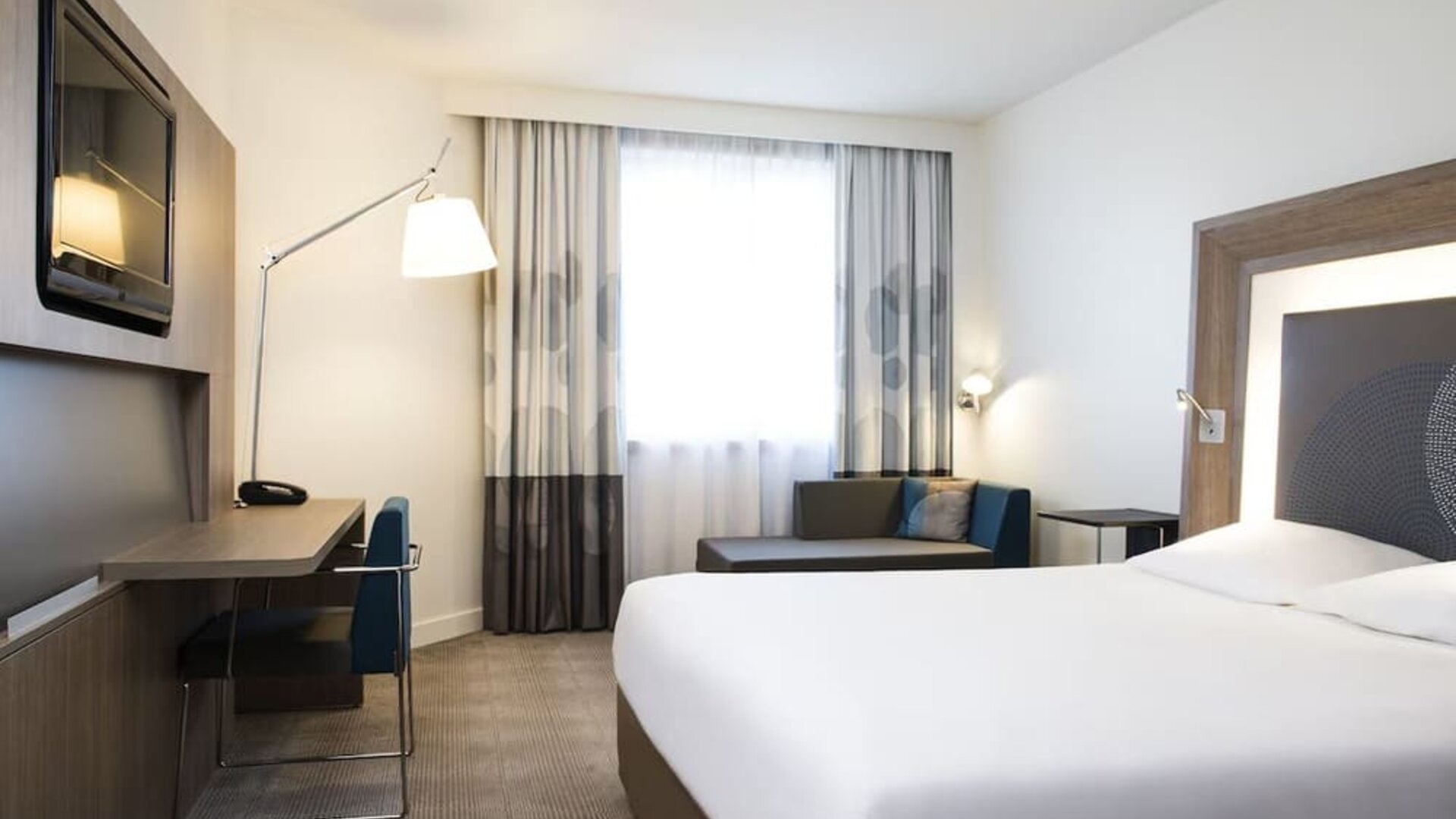 King bed with TV and sofa at Novotel Toronto North York.