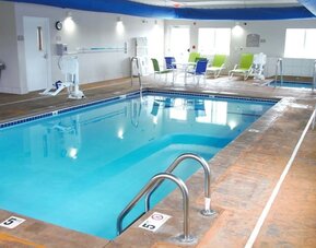 Indoor pool with seating area at Coratel Inn & Suites By Jasper Rochester.