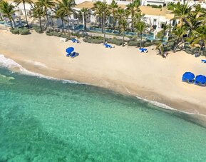 Oyster Bay Resort's beach with sun tanning chairs and waves going on shore. 