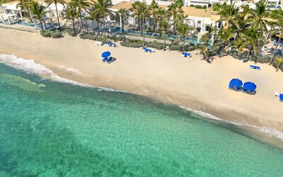 Oyster Bay Resort's beach with sun tanning chairs and waves going on shore. 