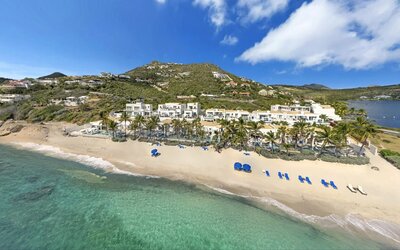 Oyster Bay Resort buildings, palm trees, coastline with tropical water shining. 