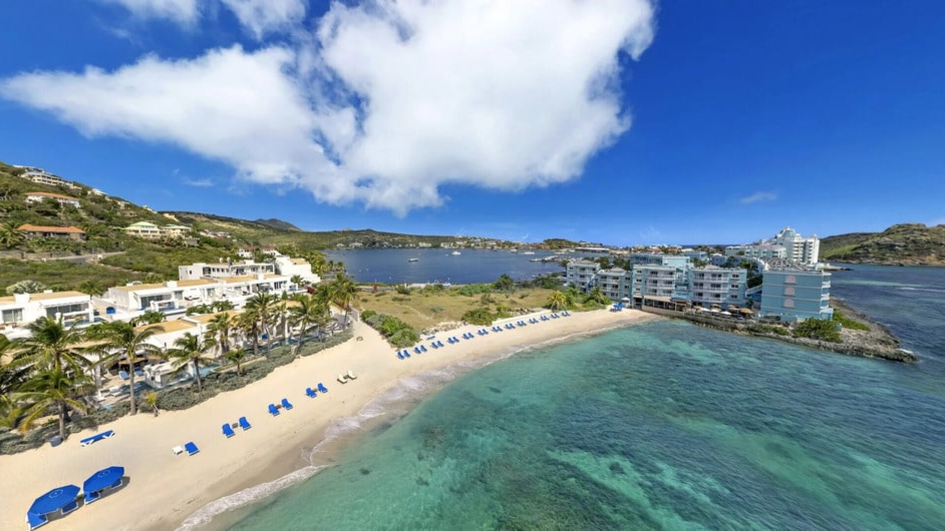 Oyster Bay Resort in St. Martin with beach chairs lined along beach. 