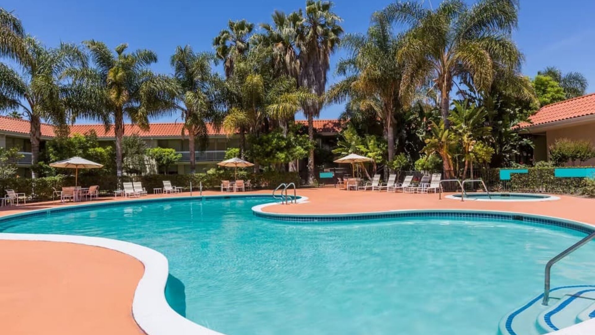 Outdoor pool with palm trees at Uptown Oasis San Jose Airport.