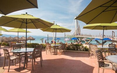 Outdoor seating with beach umbrellas at Hotel Delfin PV Beach Resort.