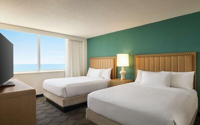 Two queen beds with TV and ocean view at Embassy Suites By Hilton Deerfield Beach Resort & Spa.