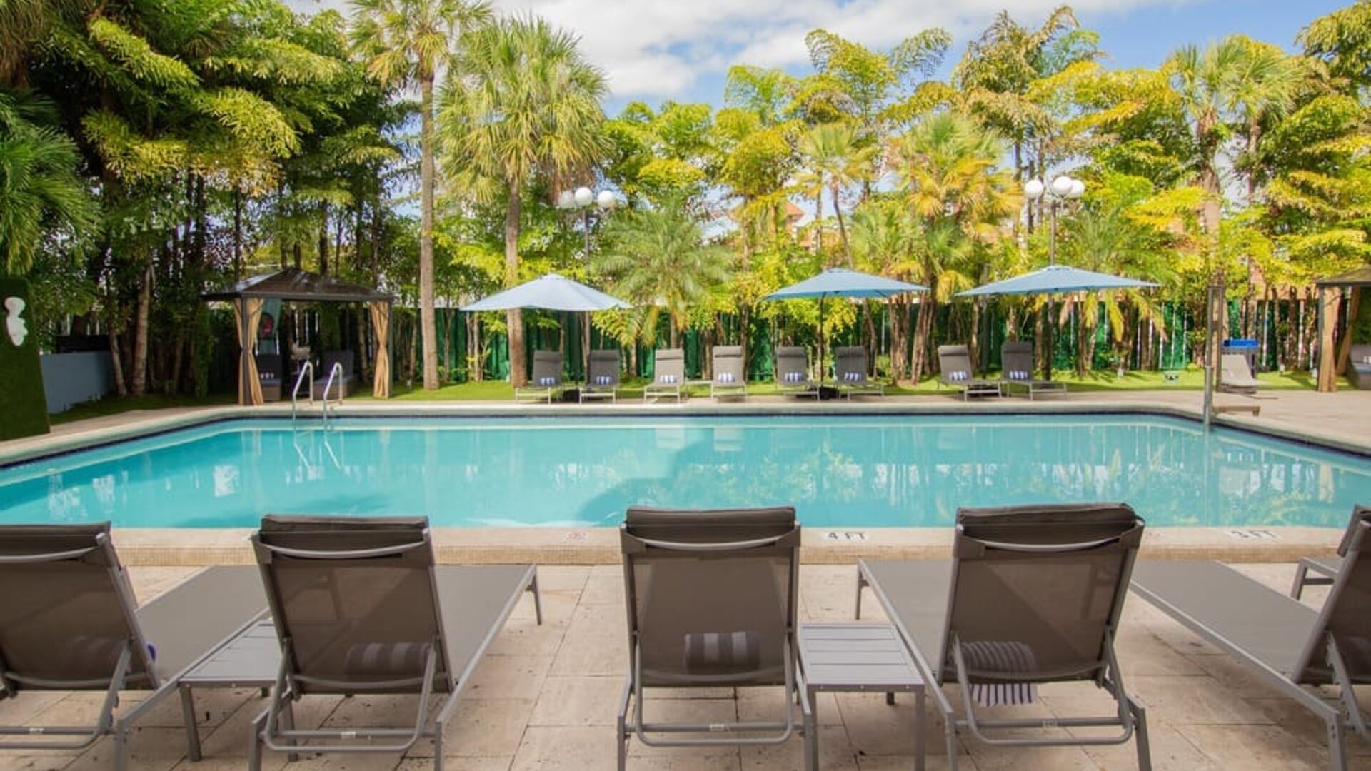 Outdoor pool with loungers at Regency Miami Airport By Sonesta.