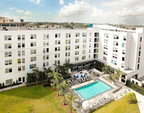 Hotel pool and hotel exterior at Aloft Miami Doral.
