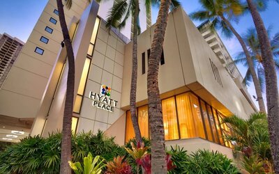 Hotel exterior with palm trees at Hyatt Place Waikiki Beach.
