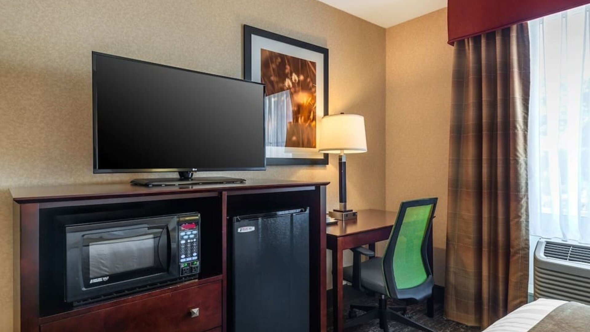 In-room workspace with desk, ergonomic chair, flat-screen TV, microwave, and mini refrigerator at Best Western Braintree.