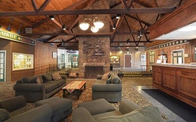 Welcoming lodge-style lounge with comfortable seating, fireplace, and rustic architectural details at Sturbridge Host Hotel.