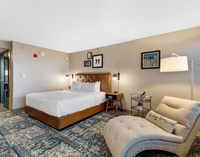 Spacious king guest room featuring a comfortable seating area, modern amenities, and contemporary décor at Four Points by Sheraton Boston-Newton.