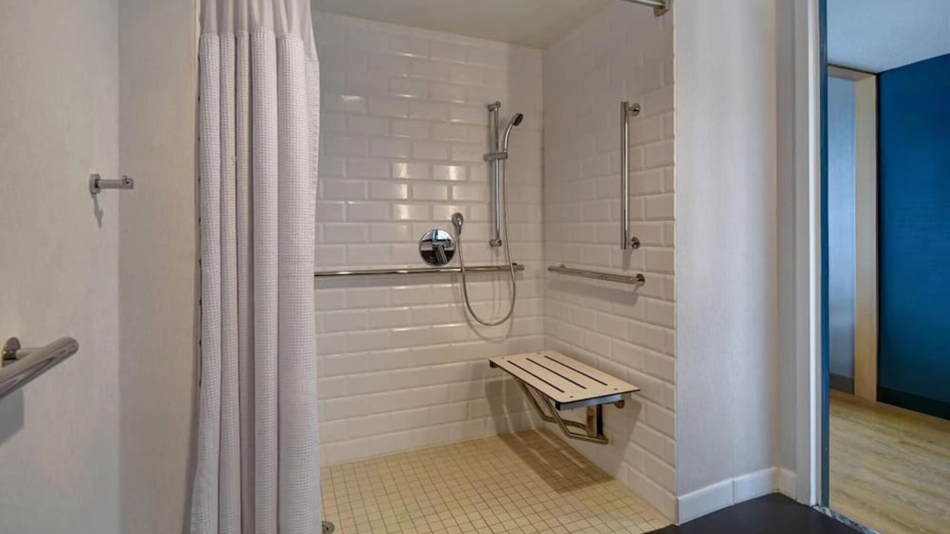 Accessible roll-in shower with grab bars, seating, and mobility-friendly features designed for guest comfort at Four Points by Sheraton Boston-Newton.