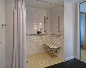Accessible roll-in shower with grab bars, seating, and mobility-friendly features designed for guest comfort at Four Points by Sheraton Boston-Newton.