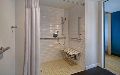 Accessible roll-in shower with grab bars, seating, and mobility-friendly features designed for guest comfort at Four Points by Sheraton Boston-Newton.