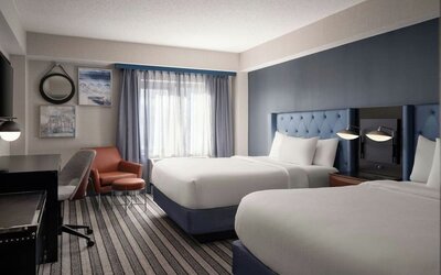 Double queen guest room offering comfortable accommodations, modern furnishings, and thoughtful amenities for families and groups at Courtyard by Marriott Boston Brookline.