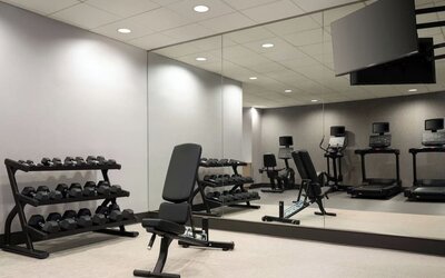 Well-equipped fitness facility with free weights, cardio machines, and mirrored workout spaces designed to support guests’ wellness routines at Courtyard by Marriott Boston Brookline.