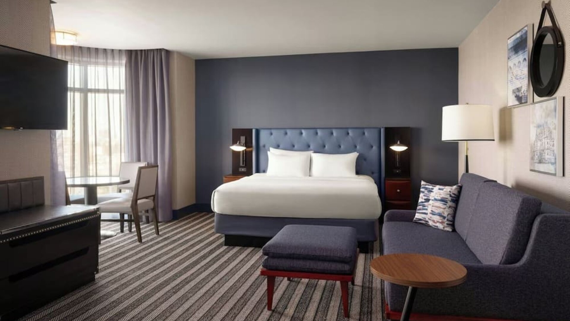 Spacious king guest room featuring a comfortable sofa, modern décor, and ample room for relaxation or extended stays at Courtyard by Marriott Boston Brookline.