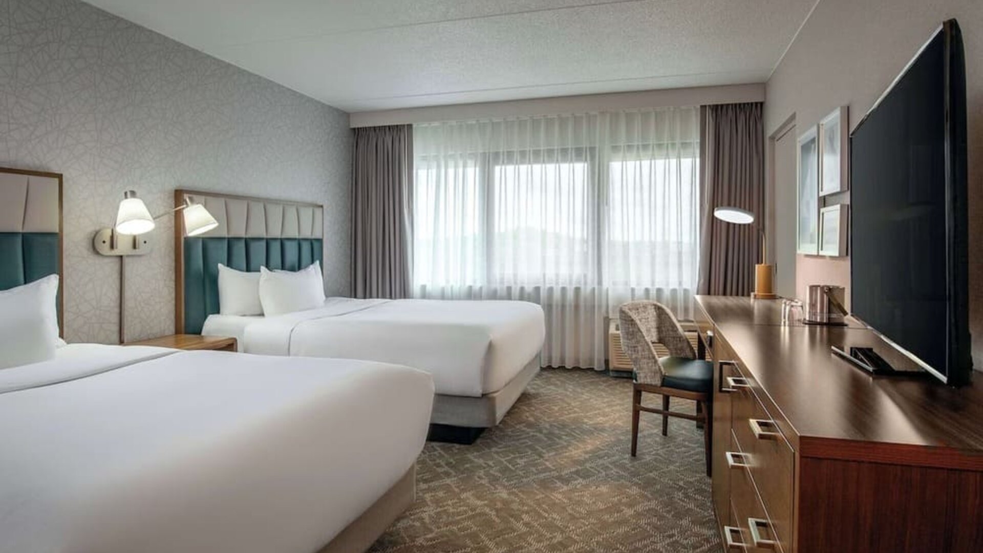 Double queen guest room featuring premium bedding, a dedicated workspace, and comfortable accommodations for business and leisure travelers at DoubleTree by Hilton Westborough.