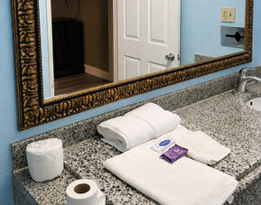 Guest bathroom vanity area featuring granite countertops, ample space, and essential amenities for a comfortable stay at Blue Way Inn & Suites Wichita East.