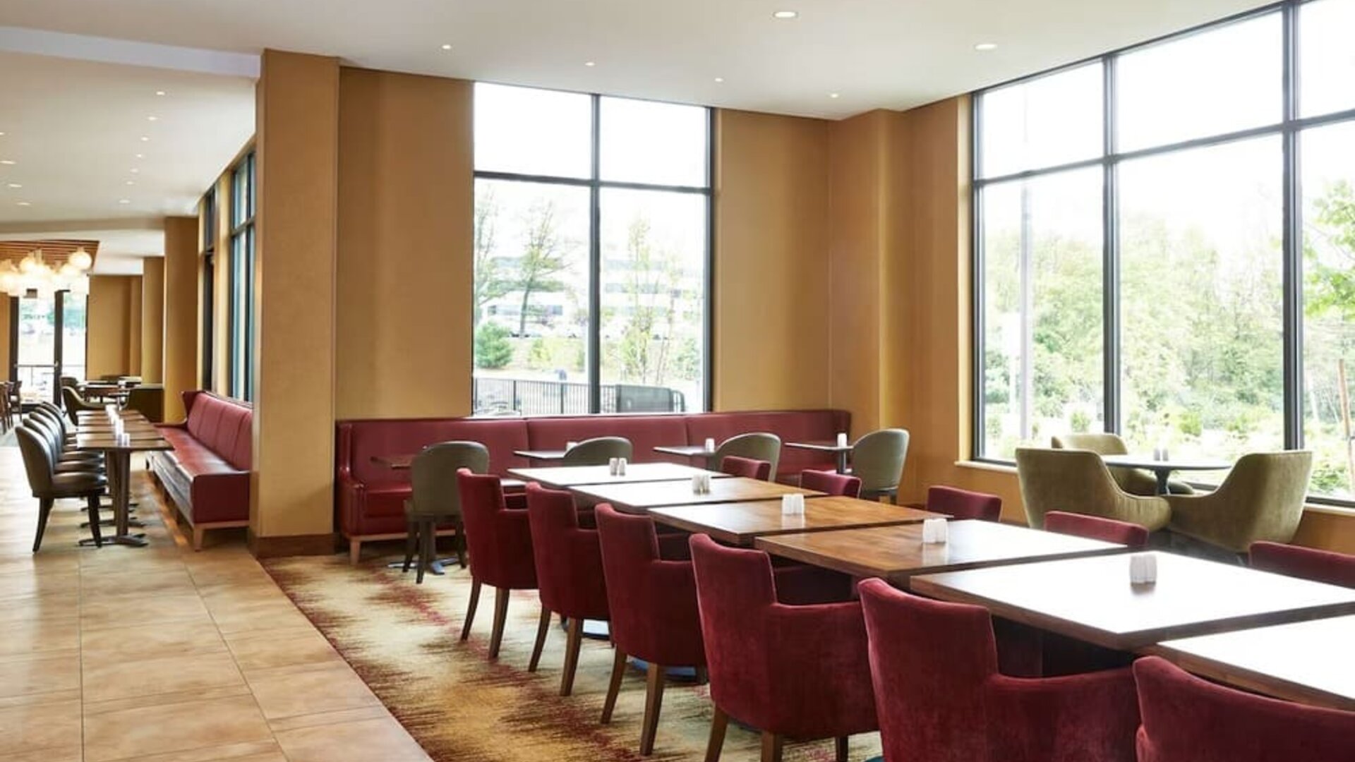 Bright dining area featuring floor-to-ceiling windows, comfortable seating, and a welcoming setting for breakfast, lunch, or casual gatherings at Hilton Garden Inn Boston/Marlborough.